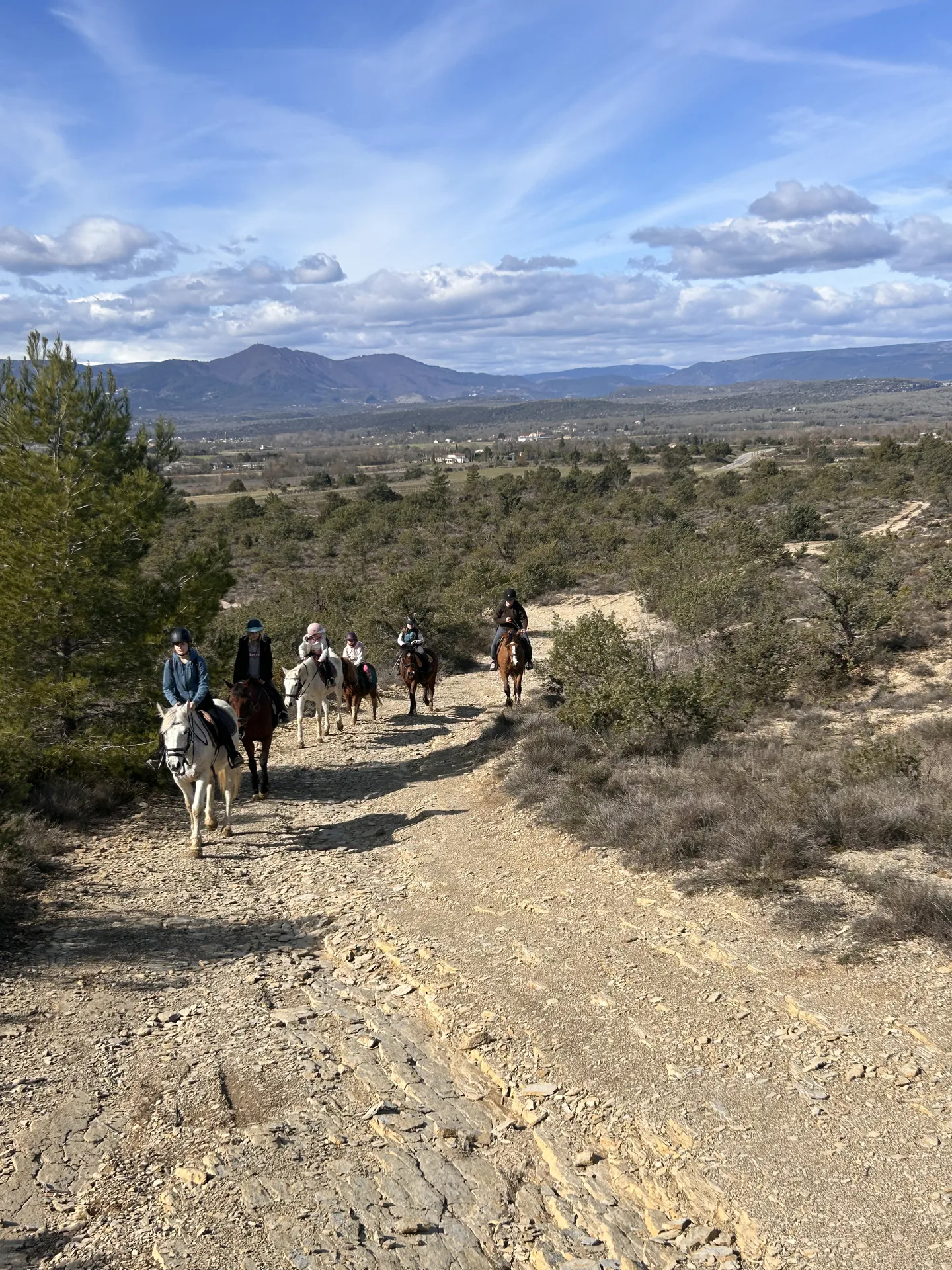 Des cavaliers sur un chemin dans un paysage de collines