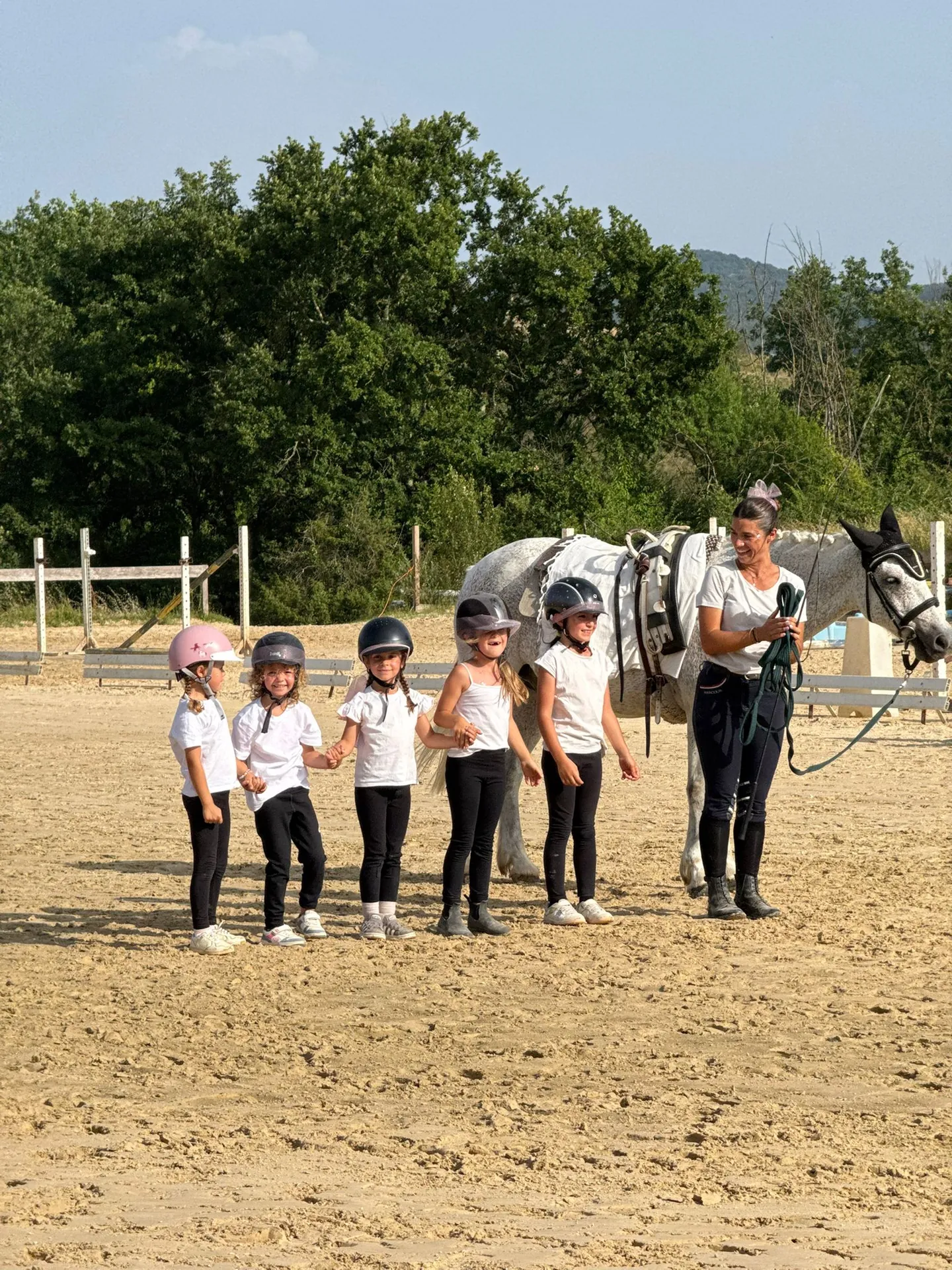 Des enfants casqués réunis près d’un poney avec une accompagnatrice