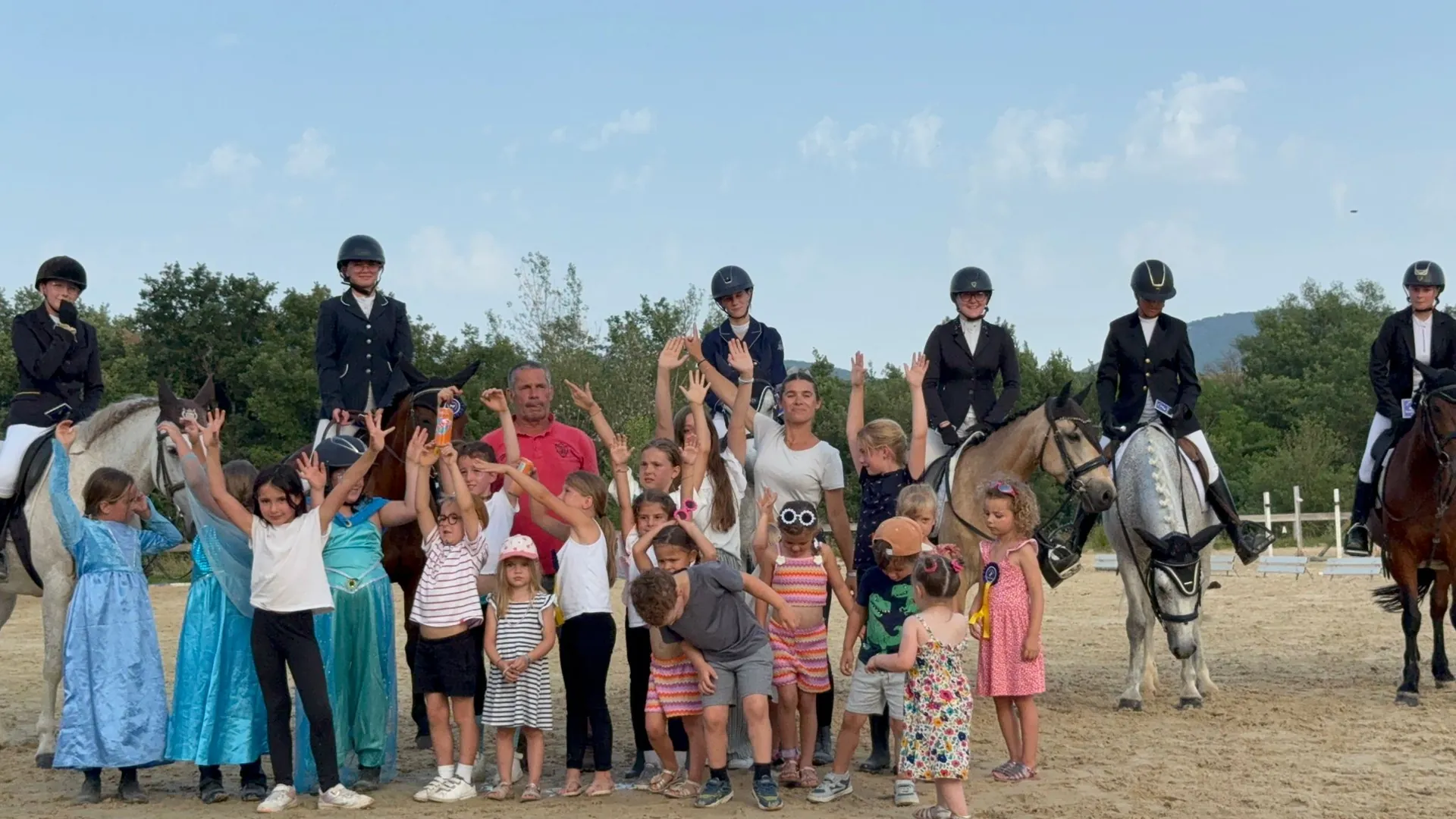 Un groupe d’enfants et de cavaliers réunis devant les chevaux dans la carrière