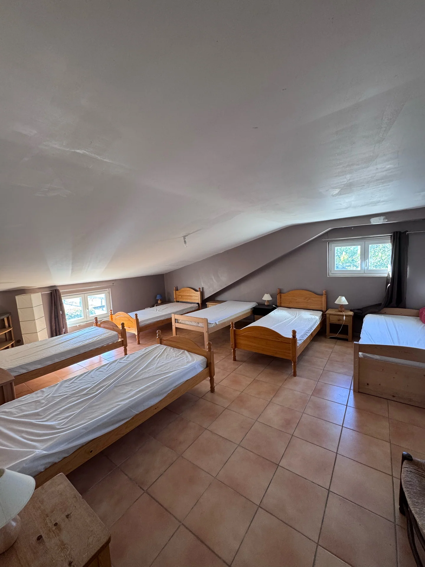 Le dortoir du gîte sous les combles, avec ses lits en bois et ses deux fenêtres